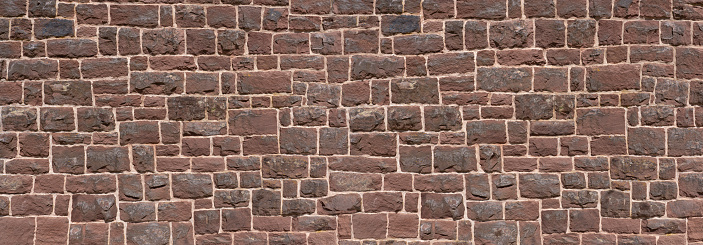 Old panoramic wall made of red sandstone - closeup of a church wall made of many square natural stones