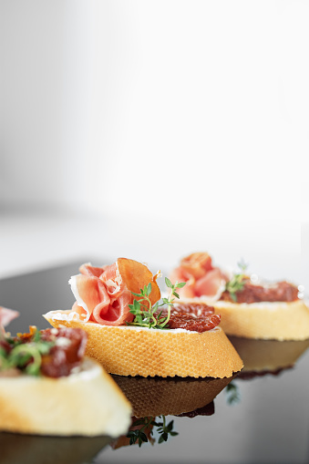 Appetizer with prosciutto, bruschetta and sun-dried tomato. Food, restaurant and event concept. Close-up.