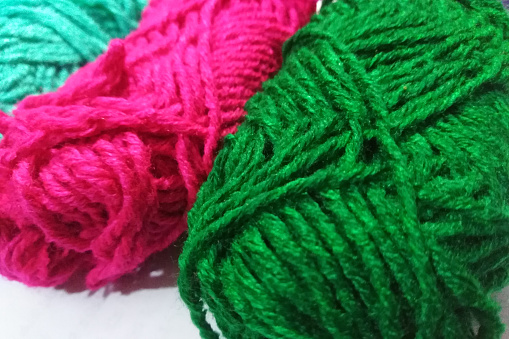 Wool yarn on white background. Apparel material for knitting fabrics. Green and Pink yarn.