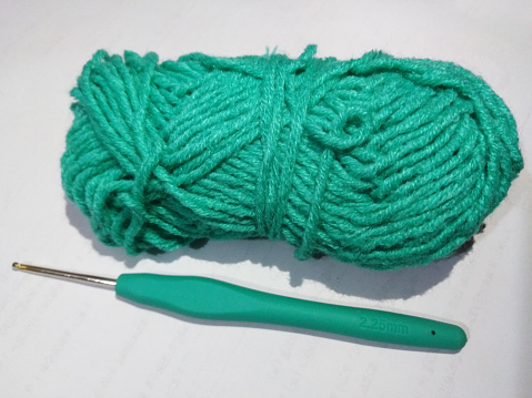 blue ball of yarn with crochet hook on white background