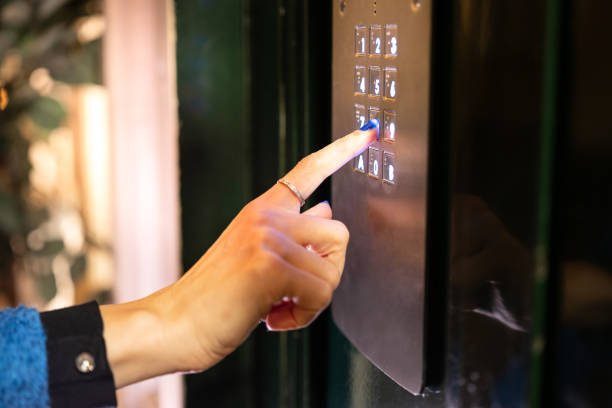 Close up on a woman's hand typing numbers to enter an apartment building at night.