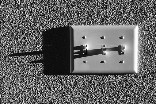 Light switc for several lights with long dark shadows on wall