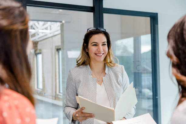 istock Smiling real estate agent reviews paperwork with unrecognizable female clients 1445482902