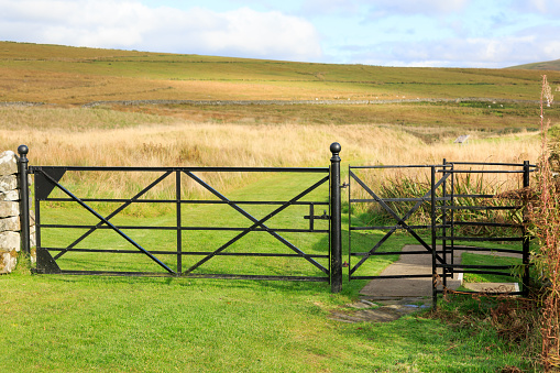 Black coloured five bar iron gate with iron Kissing gate fitted to the righthand side looking out over farmland meadows