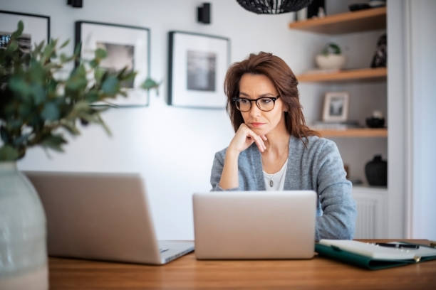 istock Confident woman using laptop while sitting at table at home 1445483768