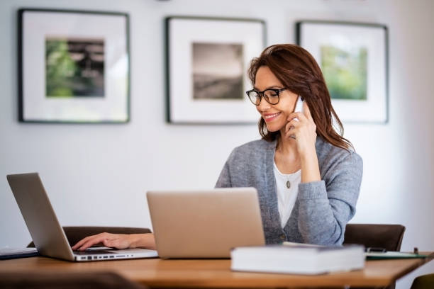 istock Businesswoman using mobile phone in front of laptop while working from home 1445483770