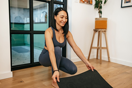 Mid adult asian woman getting ready to exercise yoga