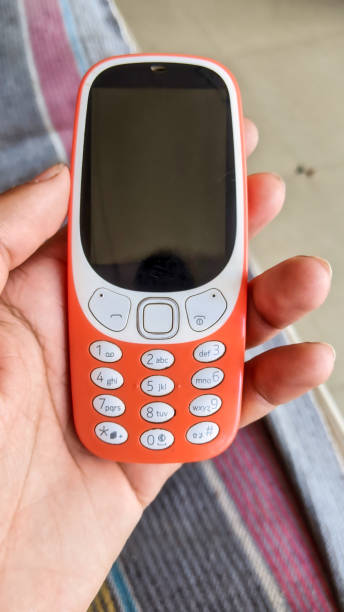 istock A keypad phone with buttons isolated on black background. Old Cell phone with black display. Closeup of a 2g, 3g orange mobile in India. Technology and social concept. 1445485823