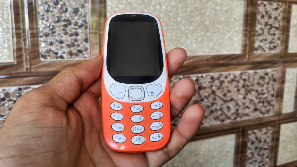 istock A keypad phone with buttons isolated on black background. Old Cell phone with black display. Closeup of a 2g, 3g orange mobile in India. Technology and social concept. 1445485833