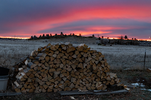 Sunrise colors over stack of firewood on the prairie of Golden Valley, Montana, USA