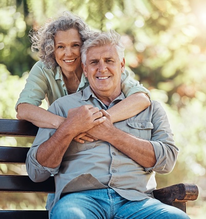 Love, portrait and elderly couple hug and bonding in a park, happy and relax in nature together. Retirement, care and senior man and woman enjoying relationship and relaxing lifestyle with affection