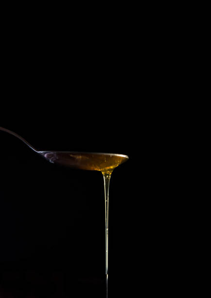 istock Close-up of honey dripping from spoon on a black background. 1445492501