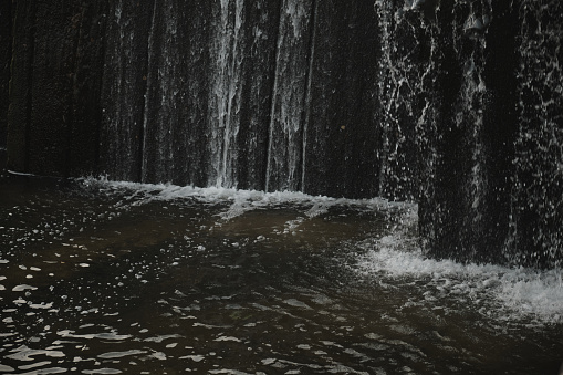 A waterfall flowing at park Wall of water A beautiful view of the falling water cascade city fountain close-up pouring