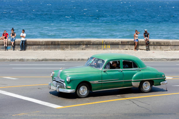 Havana, Cuba - April 10, 2018: A vintage American convertible car with tourists driving along the seaside promenade Malecon in Havana, Cuba.