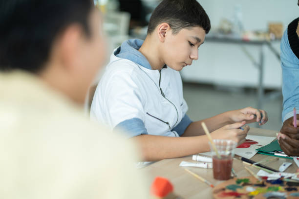 istock Boy enjoy drawing and painting in arts class. kid using paintbrush sketch on paper. practicing art skill, teacher support creative thinking idea. school activity, learning and education concept 1445501888