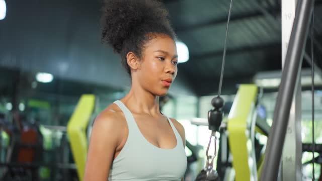 African American sportswoman lift up weight machine or barbell in gym. Attractive young athlete female workout exercise use weight equipment tool for health care and maintain muscle in fitness club.