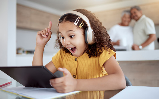 Excited, homeschool tablet or girl with ideas, learning motivation or education innovation in homework study on headphones. Smile, happy and student child with technology in senior grandparents house