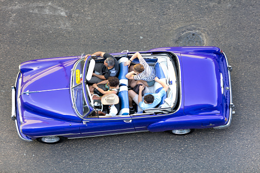 Havana, Сuba - April 10, 2018: Tourists drivimg in a classic American car on the Malecon in Havana, Cuba, elevated view.