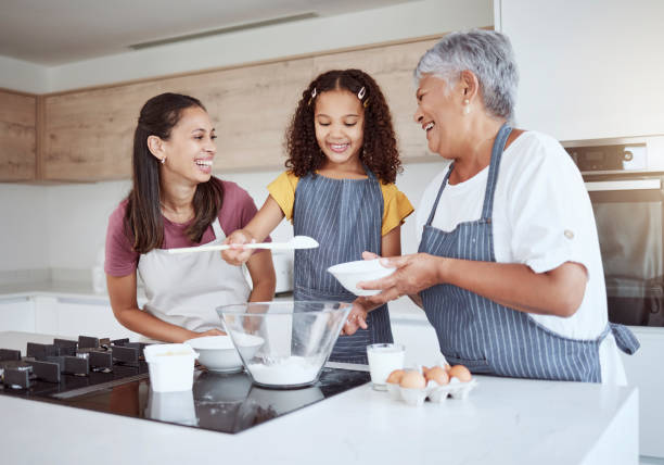 istock Happy family, cooking and baking in kitchen child development, learning and skills activity. Brazilian grandmother, mother and girl bonding through teaching or support food process at house 1445510117