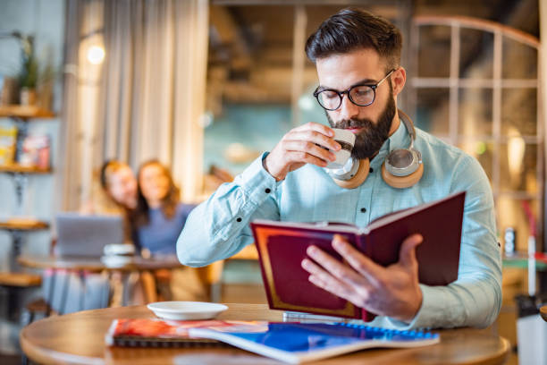 istock Man reading a book in university cafe 1445511240