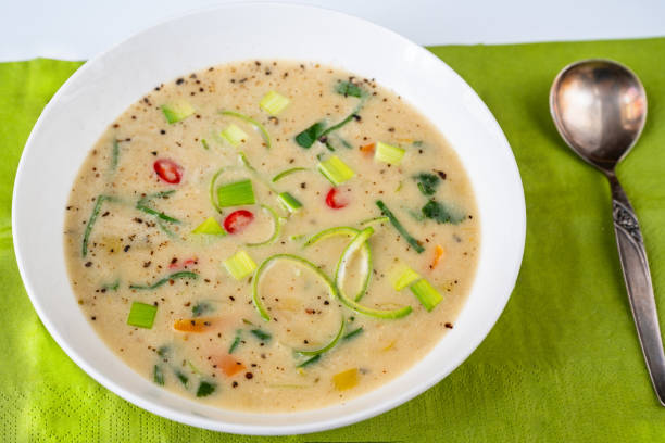 Leek soup with chilli pepper in white plate, green background, closeup. stock photo