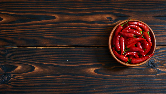 Red Hot Chili Peppers in wooden bowl on dark wooden background