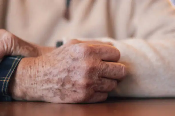 Wrinkled hands of an elderly man on a table close-up