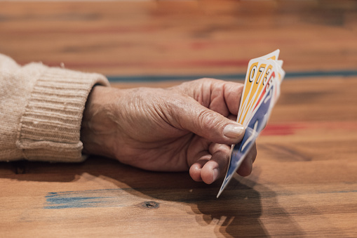 Hand of an elderly man playing cards on the table