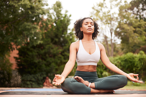 Mid adult black female in the yoga asana Padmasana in quiet meditation. Full length with copy space