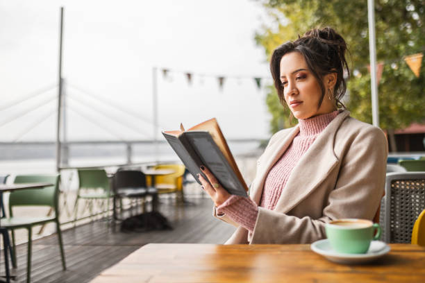istock Young woman drinking coffee and enjoying a book 1445518899