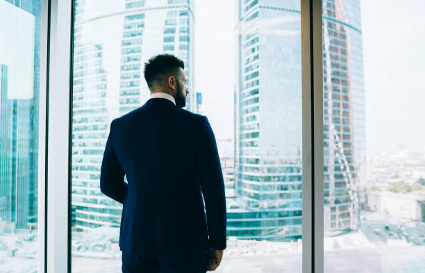 istock Businessman looking out window on city 1445520015