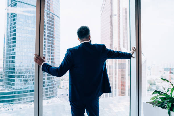 istock Successful businessman looking through window at city 1445520160