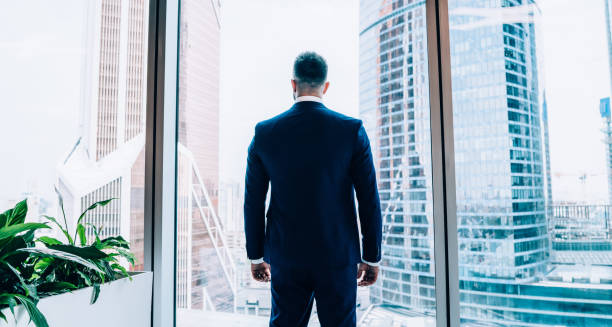 istock Confident businessman looking through window at downtown in office 1445522447