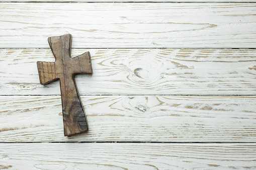 dark wooden cross on white wooden board in horizontal position. space copy. space for text. religious background.
