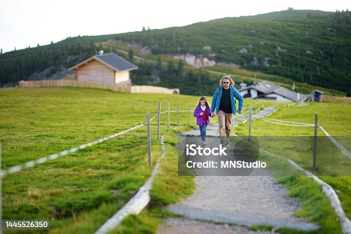 istock Father and his little daughter hiking in South Tyrol, Renon/Ritten region, Italy. Beautiful Alpine village on a background. 1445526350