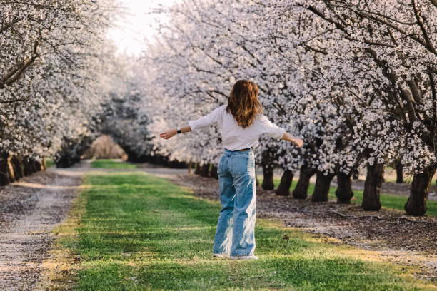 istock Woman enjoying springtime among blooming almond trees 1445527347