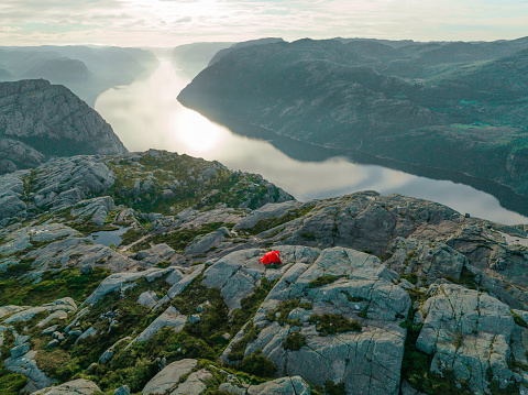 Scenic aerial view of woman setting up at tent on the background of Lysefjord