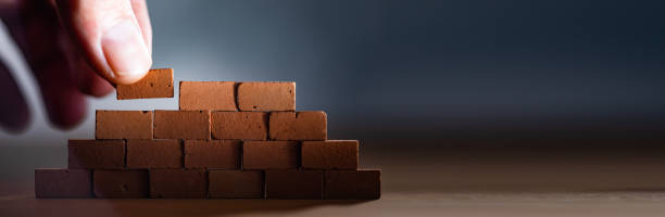 istock Hand placing wooden blocks stacked collapse prevention 1445528010