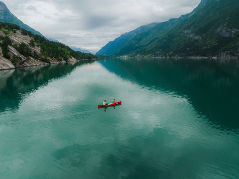 Scenic aerial  view of young  man and woman canoeing on the lake in Norway