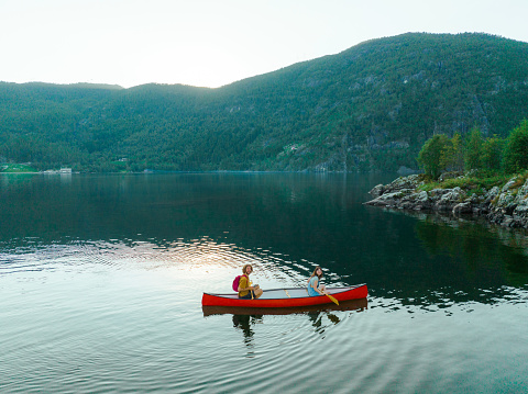 Scenic aerial  view of young  man and woman canoeing on the lake in Norway
