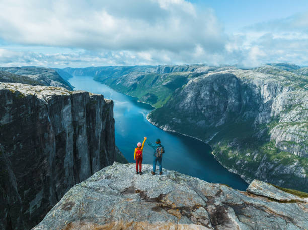vista aérea do homem e da mulher que levantam os braços de segurar nas montanhas em noruega - destino de viagem - fotografias e filmes do acervo