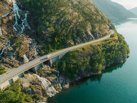 Scenic aerial view of road near waterfall that falls into fjord in Norway