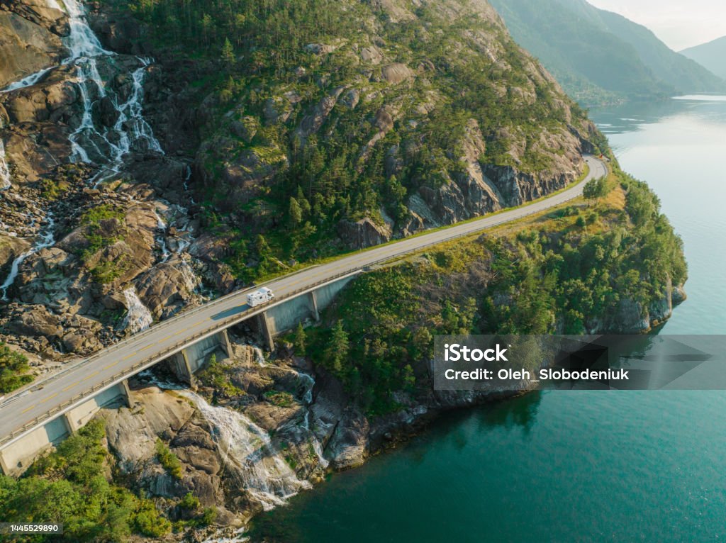 Aerial view of road near waterfall that falls into fjord in Norway Scenic aerial view of road near waterfall that falls into fjord in Norway Landscape - Scenery Stock Photo