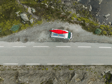 Scenic aerial view of white  camper van with red boat on the  road through Norwegian highlands