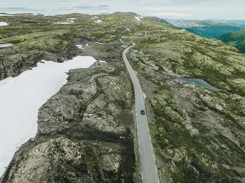 Scenic aerial view of car on the road through Norwegian highlands in fog