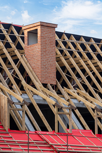 detail of unfinished building, new rooftop with wooden framework and red brick chimney, vertical shot