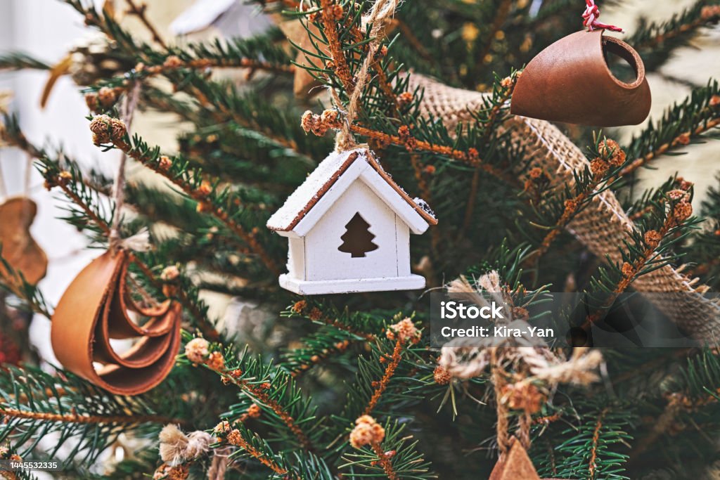 Vintage wooden toy house on Christmas tree. Natural Xmas ornaments for Christmas tree, zero-waste Vintage wooden toy house on Christmas tree. Natural Xmas ornaments for Christmas tree, zero waste, soft focus Christmas Stock Photo