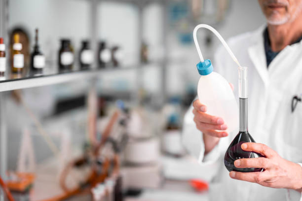 Close up on male technician's hands holding a test tubes while all the rest of chemical equipment is around him during a biochemical experiment.