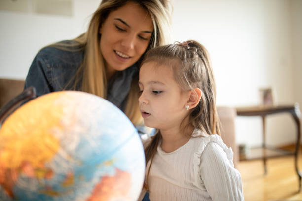 woman spending some great time with little girl at home and exploring globe - earth globe mother child imagens e fotografias de stock