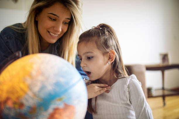 istock Woman spending some great time with little girl at home and exploring globe 1445538794